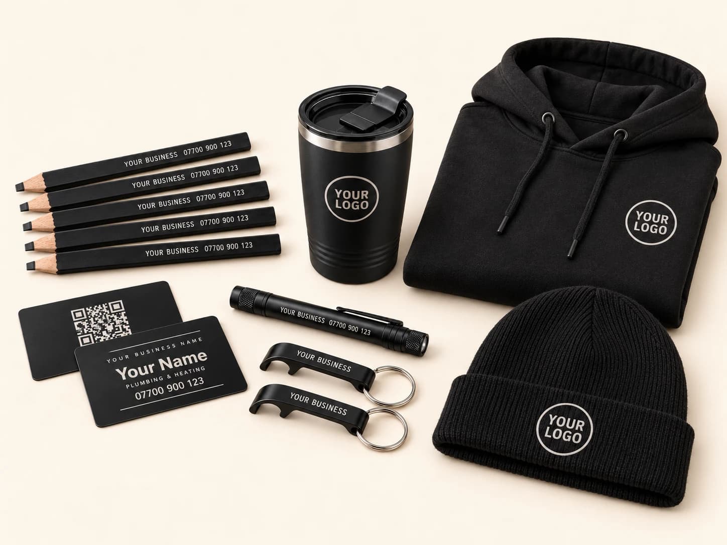 The full kit laid out: five flat black carpenter pencils, a black metal business card shown front and back, a matte black insulated tumbler, a black penlight and two black keyring bottle openers, each engraved in silver, with a folded black hoodie and a black beanie, both carrying a sample logo.